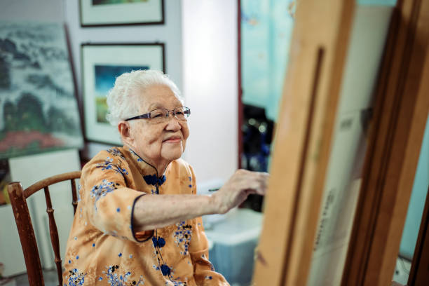 Asian chinese smiling senior women painting on canvas at her house waist up of active mature senior women painting on canvas with easel 90 plus years photos stock pictures, royalty-free photos & images