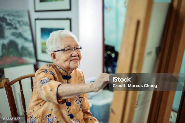 Asian Chinese Smiling Senior Women Painting On Canvas At Her House Stock Photo - Download Image Now