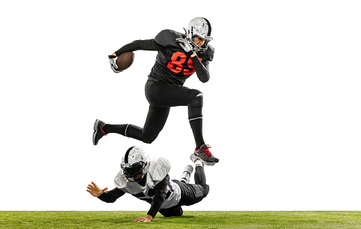 Running forward. Two american football players in action, motion. Sportsmen fight for ball isolated on white background on grass. Concept of sport, challenges, achievements, active lifestyle.