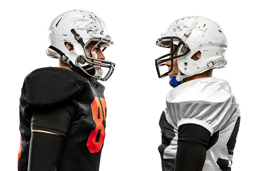 Close-up american football players standing opposite each other before start of match isolated on white background on grass Concept of sport, challenges, achievements, active lifestyle.