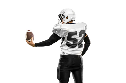 Back view. Studio shot of strong athlete, american football player wearing sports uniform posing isolated on white background. Sportsman in uniform with ball looks inspired, confident.