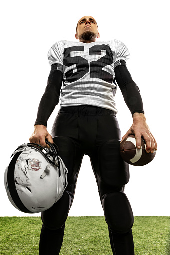 Bottom view of american football player posing isolated on white background. Sportsman in uniform with ball looks inspired and confident. Concept of motion and action, sport, lifestyle.