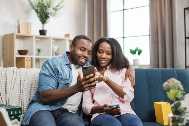 istock Loving couple sitting on couch and using smartphones 1363834406