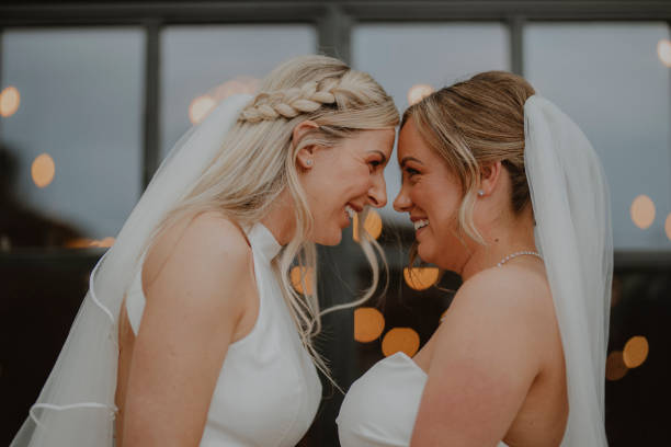 I'll Love You Forever Medium shot of two women celebrating at their LGBTQI+ wedding in the North East of England. They are both holding hands, looking at each other after saying their wedding vows. civil partnership stock pictures, royalty-free photos & images