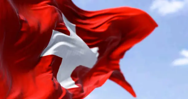 Photo of Detail of the national flag of Switzerland waving in the wind on a clear day