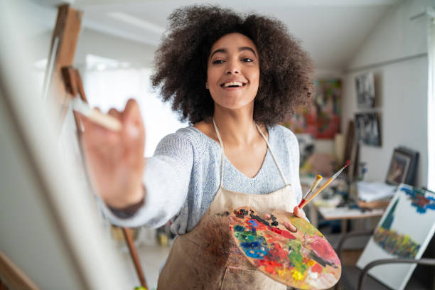istock Afro female fine artist  drawing in studio on a canvas, placed on a tripod 1363837231