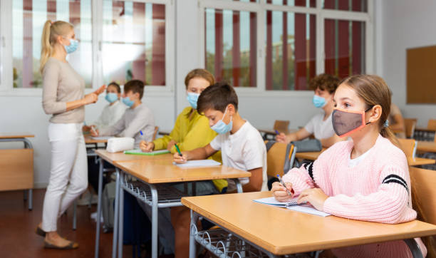 istock Schoolgirl in mask sitting in classroom 1363838948
