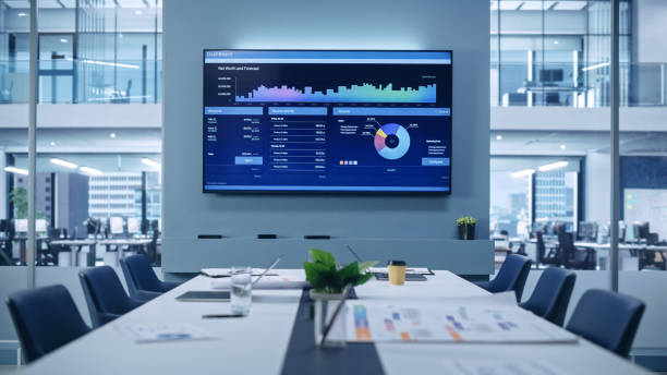 istock Modern Empty Meeting Room with Big Conference Table with Various Documents and Laptops on it, on the Wall Big TV with Big Data, Statistics, Talks about Company Growth. Contemporary Designed Workplace. 1363841475
