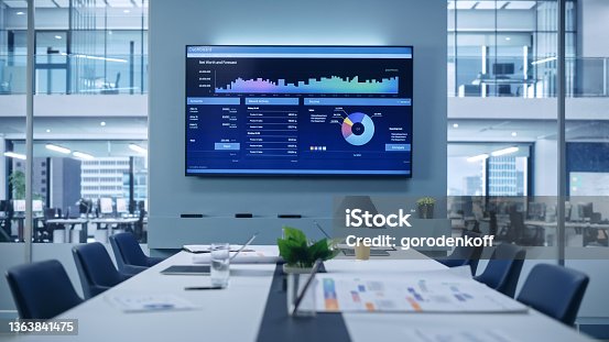 istock Modern Empty Meeting Room with Big Conference Table with Various Documents and Laptops on it, on the Wall Big TV with Big Data, Statistics, Talks about Company Growth. Contemporary Designed Workplace. 1363841475