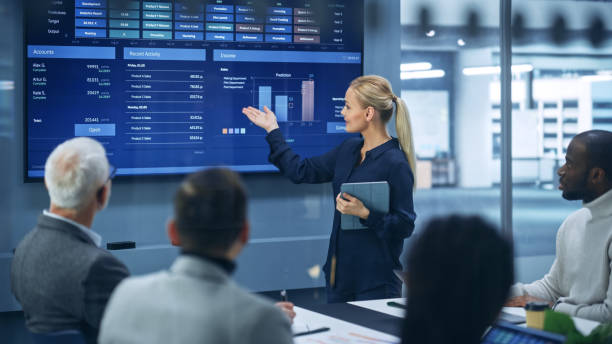 istock Diverse Modern Office: Successful Businesswoman Uses TV Screen with Big Data, Statistics, Talks about Company Growth, Discusses Strategy with Investors. Information Technology Expert Talks 1363841485