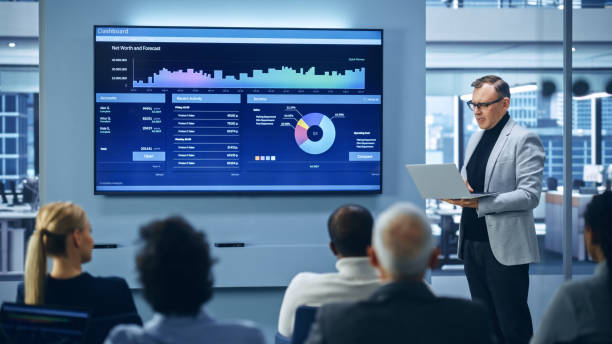 istock Modern Product Presentation Event: On-Stage Successful Caucasian Businessman Speaker Presents e-Commerce Startup Big Data Statistics, Charts, Revenue Growth Infographics. Live Event. Press Conference 1363841607