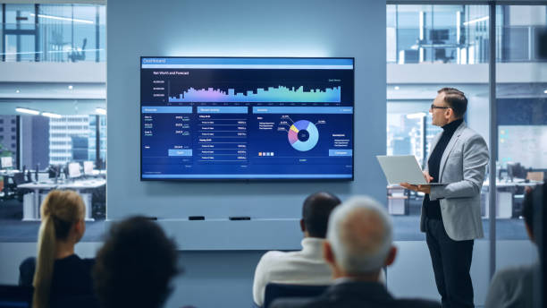 istock Modern Product Presentation Event: On-Stage Successful Caucasian Businessman Speaker Presents e-Commerce Startup Big Data Statistics, Charts, Revenue Growth Infographics. Live Event. Press Conference 1363841627