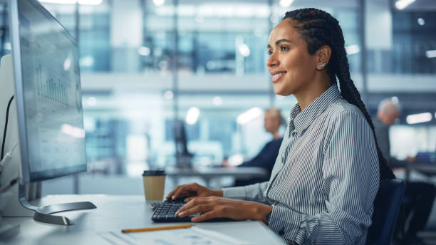 corporate office: black female it technician using desktop computer, uses big data statistics, graphs. smiling creative software engineer work on ecommerce project marketing, development. - hair net imagens e fotografias de stock