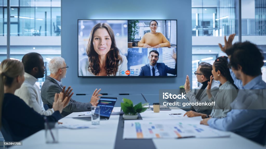 Video Conference Call in Office Boardroom Meeting Room: Executive Directors Talk with Group of Multi-Ethnic Entrepreneurs, Managers, Investors. Businesspeople Discuss e-Commerce Investment Strategy Video Call Stock Photo