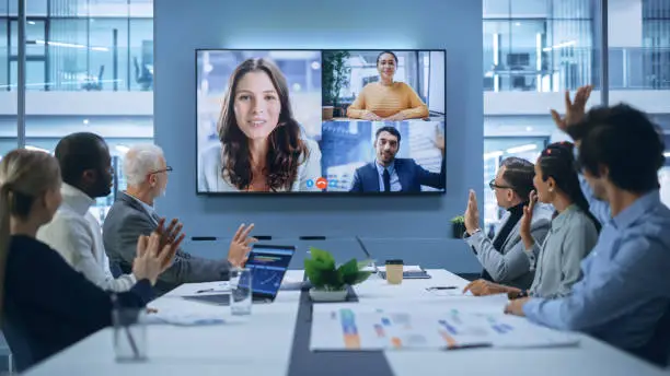 Photo of Video Conference Call in Office Boardroom Meeting Room: Executive Directors Talk with Group of Multi-Ethnic Entrepreneurs, Managers, Investors. Businesspeople Discuss e-Commerce Investment Strategy