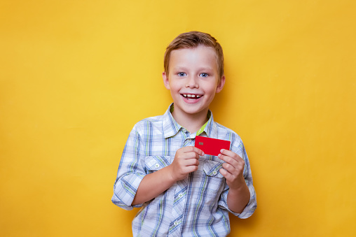 Child holding card. Funny kid with bank card, empty blank, copy space. Discount and payment