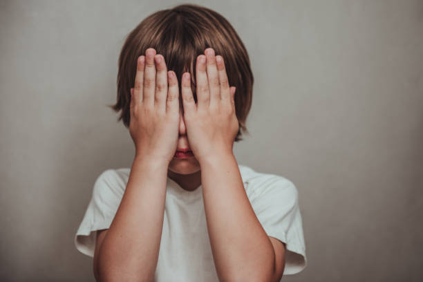 Boy crying covered his face with his hands. Stressed child. Domestic Family violence and aggression concept violence Boy crying covered his face with his hands. Stressed child. Domestic Family violence and aggression concept violence crying stock pictures, royalty-free photos & images