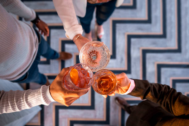 Cheers to the Weekend A high angle shot of an unrecognisable multi-ethnic group of friends wearing smart-casual clothing in a bar in Newcastle Upon Tyne. They are all making a celebratory toast with cocktails. cocktail party stock pictures, royalty-free photos & images