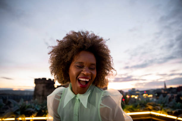 Dancing on the Rooftops A portrait shot of a mature black woman with a large afro on a rooftop bar in Newcastle Upon Tyne. She is dancing on a table as the sun sets over the city. black people bar stock pictures, royalty-free photos & images
