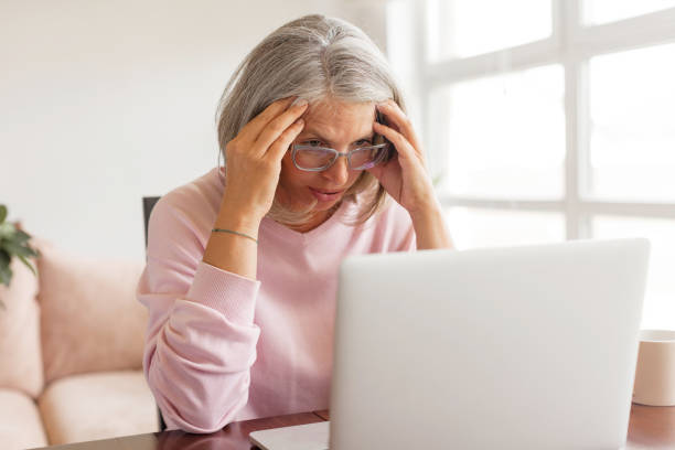 istock Sad middle-aged woman sit at table in living room using laptop 1363847971