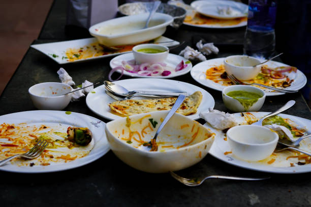 Empty dirty white plates with fork, spoon and waste food after eaten on stainless table