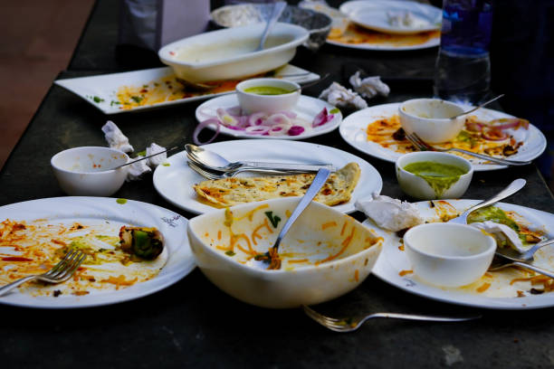 empty dirty white plates with fork, spoon and waste food after eaten on stainless table - dirt food plate fork imagens e fotografias de stock