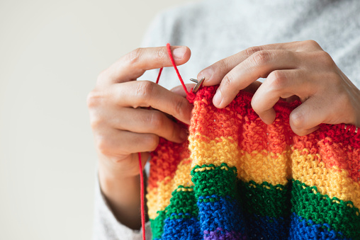 Cozy homely atmosphere. Female hobby knitting. Yarn pastel multicolor in a basket. Skeins, balls, knitting needles, hooks and scissors.