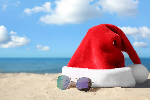 istock Santa's hat and sunglasses on sandy beach, space for text. Christmas vacation 1363851130