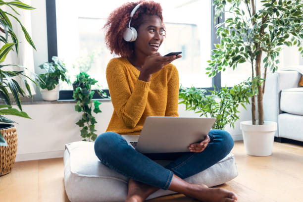 istock Pretty woman using her mobile phone while working with laptop sitting on a puff at home. 1363851674