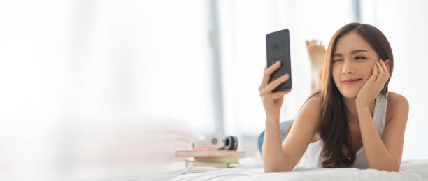 Asian Beautiful on bed taking selfie on mobile phone or smartphone.