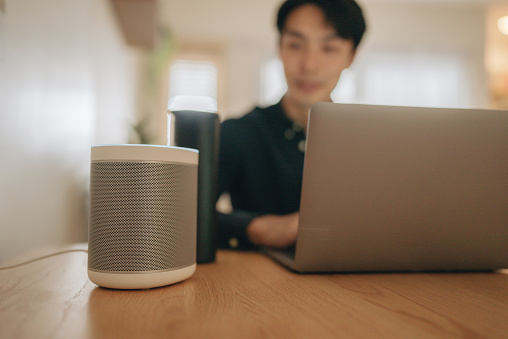 Smart AI speaker concept - asian businessman talk to voice assistant to control turn on music at home