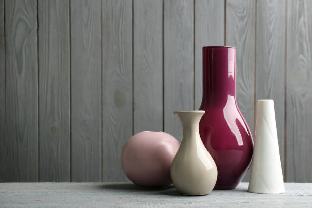 Home decor - various light colored vases on gray concrete background against blue wall. Copy space, retro style toned.