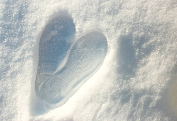 Frozen heart made by foot on white snow in winter by girl