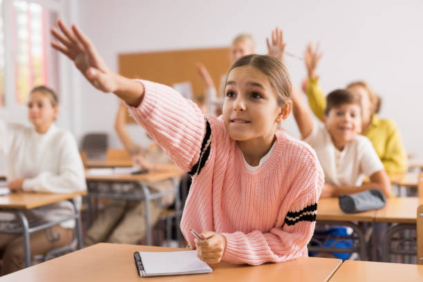 istock Young girl raising hand during lesson in school 1363856608