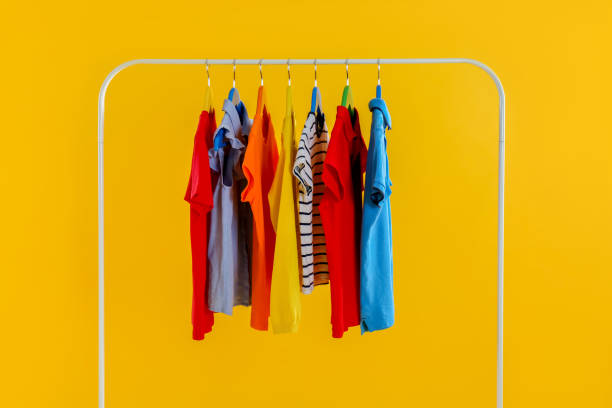 istock Rack with stylish children clothes on yellow background 1363857143