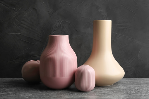 Stylish empty ceramic vases on grey table