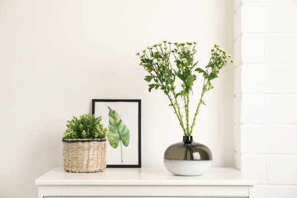 istock Decorative vase with flowers and houseplant on commode indoors 1363857448