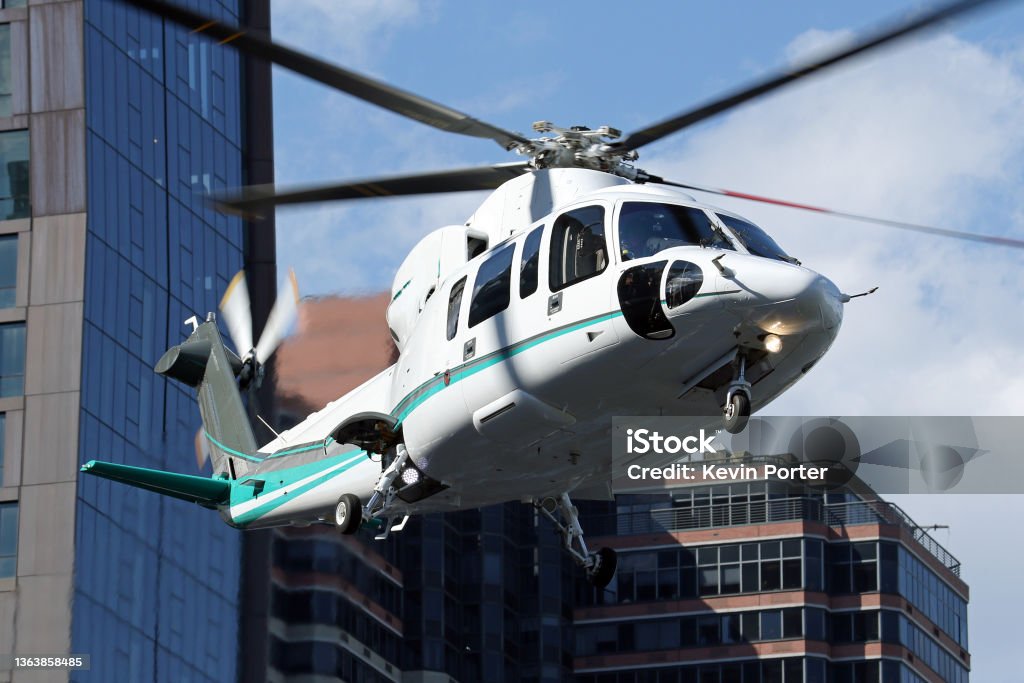 New York 34th St Heliport - Sikorsky S-76 Departing A Sikorsky S-76 helicopter departing from New York's East 34th Street Heliport. Manhattan skyscrapers in the background.  New York, New York, USA.  June 2017. Helicopter Stock Photo