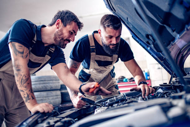 Young mechanics changing oil in car stock photo