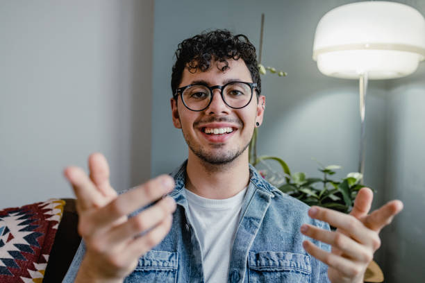 jeune homme parlant lors d’un appel vidéo et regardant la caméra - webcam photos et images de collection