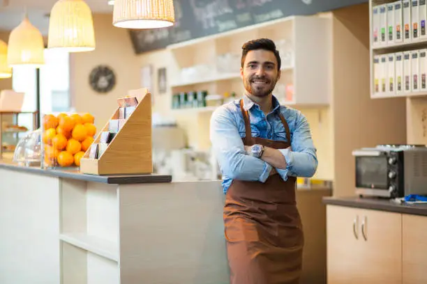Business owner in his coffee shop. Small business enterpreneur portrait. Smiling at camera.