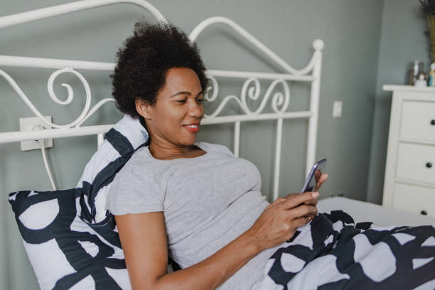 istock African-American woman using mobile phone in bed 1363864376