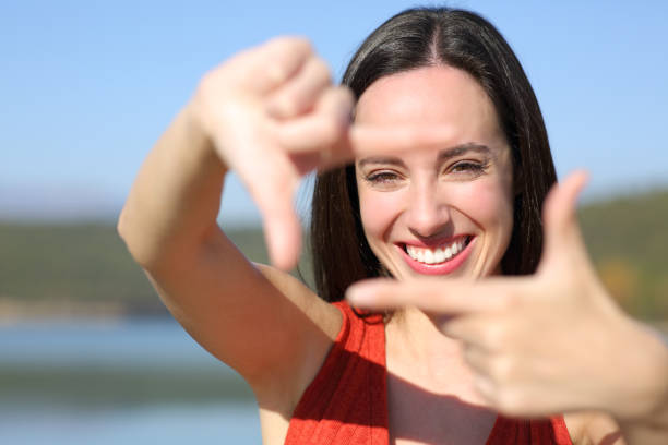 Woman smiling framing with hands at camera stock photo