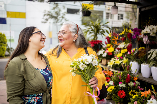 Portrait of mother and daughter. Mother is holding flowers and looking at her daughter