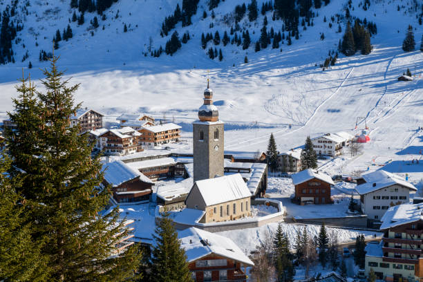 Aerial view of the small village of Zürs in the skiresort of St. Anton am Arlberg on a sunny day with snowcovered mountainrange in the background in the Arlberg Alps in Austria. Zürs and Lech am Arlberg is a highend luxury and exclusive skiresort that attracts wealthy families.
