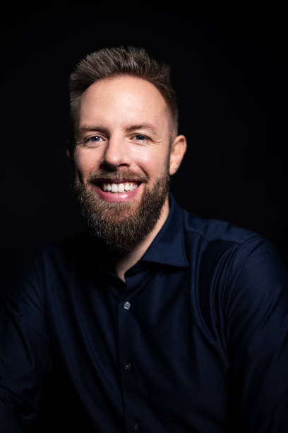 istock Young man with beard smiling at camera on black background 1363870895