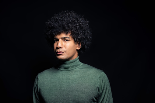 Man with serious facial expression staring at camera. Studio portrait of a north african man with afro hairstyle in a photo studio.