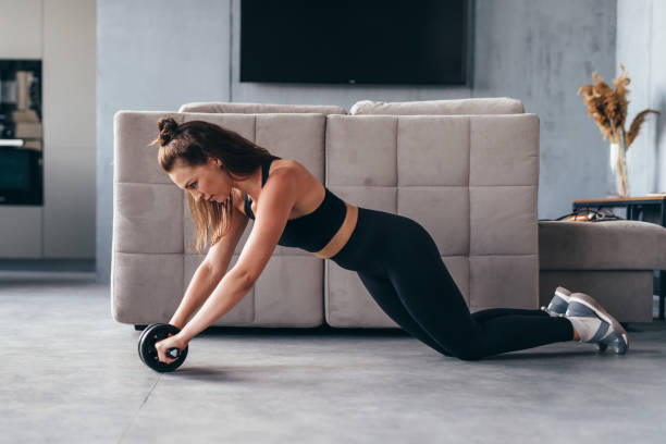 istock Fit woman working out with ab exercise wheel at home. 1363871469
