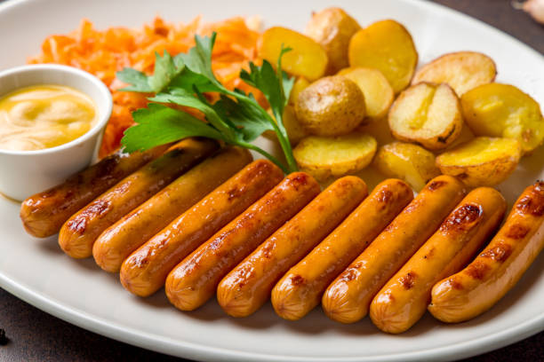 fried viennese sausages with fried cabbage and potatoes on white plate macro close up