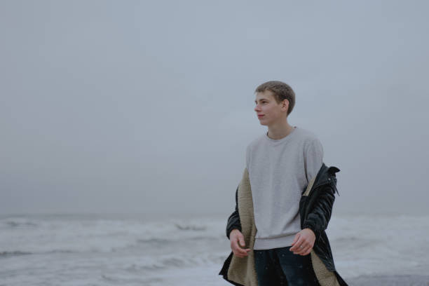 istock a young guy threw off his jacket over his shoulders looking thoughtfully aside at the sea 1363872547